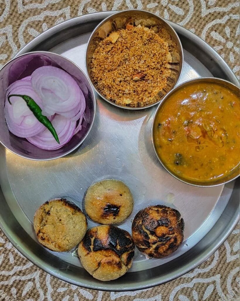 Image of a traditional Rajasthani dish, Dal Baati Churma, consisting of lentils, wheat balls, and sweet crumble, served with ghee.